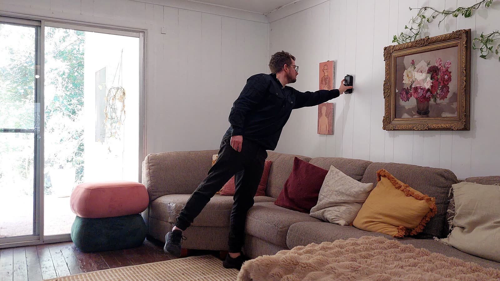 Joe taking a reading on a lounge room wall in a family home